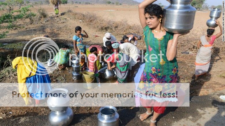 Indian Lambadi tribal villagers fill drinking water from a leaking pipe on a roadside at Chandampet Mandal in Nalgonda east of Hyderabad on April 25, in the southern Indian state of Telangana.
